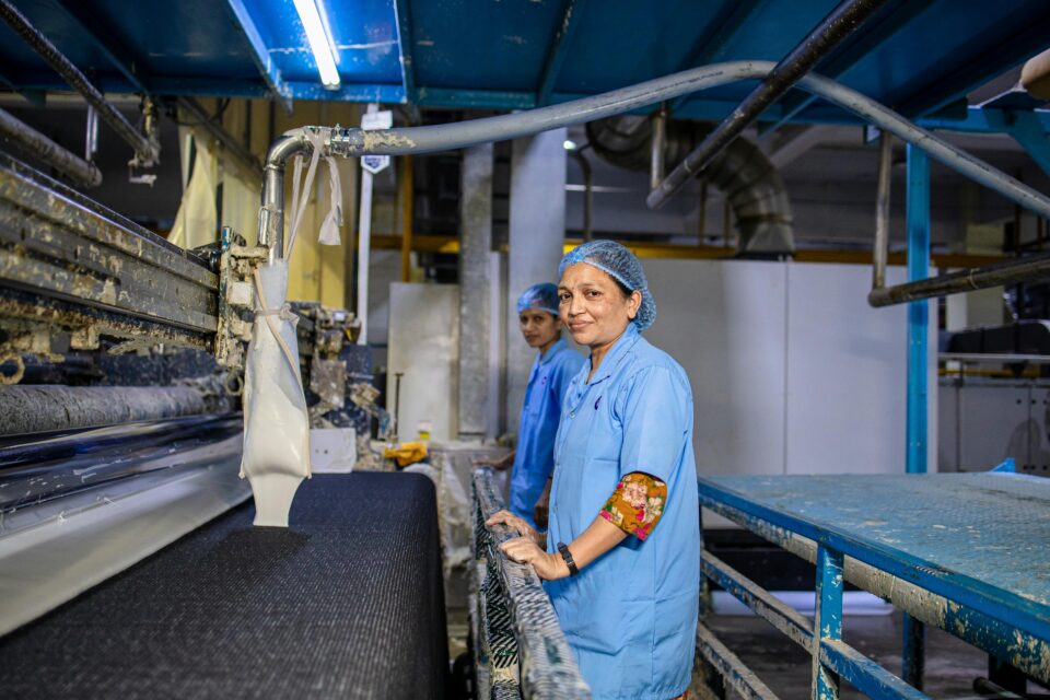 Female workers in a textile factory managing fabric production machines indoors.